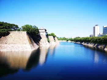 Built structures by canal against clear sky in city