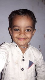 Portrait of smiling girl standing against wall