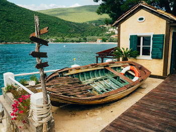 Boats moored on sea by house against mountain