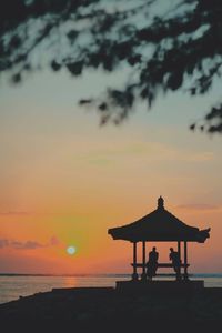 Silhouette lifeguard hut on beach against sky during sunset