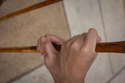 Close-up of man holding rusty prison bars