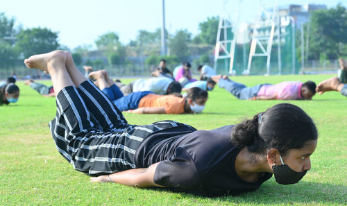 Rear view of people relaxing on field