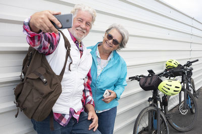 Senior woman posing with male partner for selfie against corrugated iron