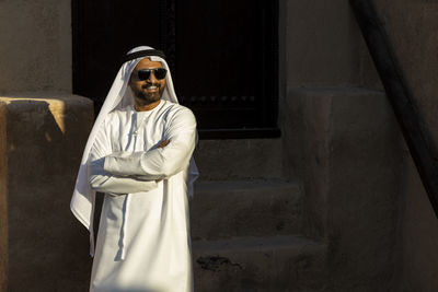 Man wearing traditional clothing standing against old built structure