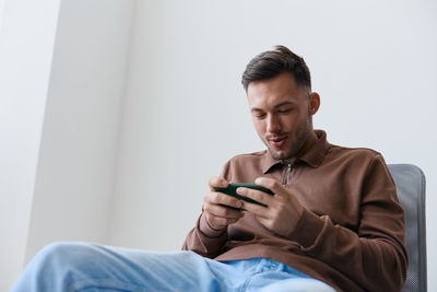 Young man using mobile phone while sitting at home