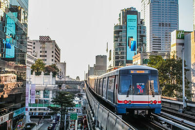 Train on railroad tracks amidst buildings in city against sky