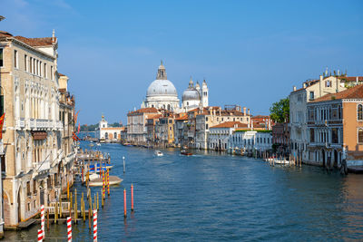 View of buildings in city by canal against sky