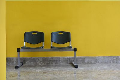Empty chair against yellow wall
