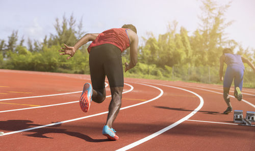 Rear view of men running on track