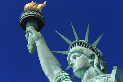 Low angle view of statue face against blue sky