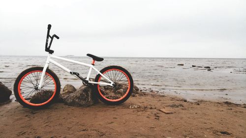 Bicycle on beach against sky