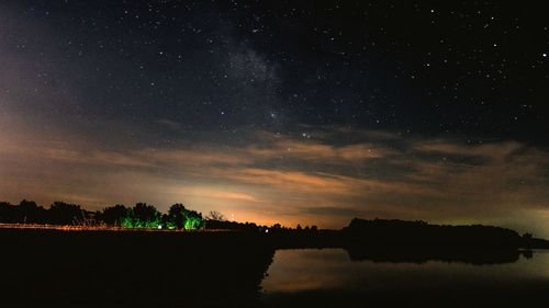 Scenic view of river by silhouette field against star field