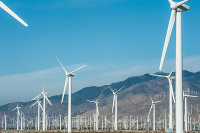 Windmills on landscape against blue sky