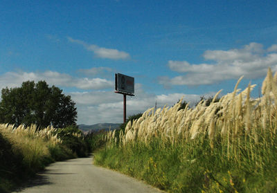 Road sign on field against sky