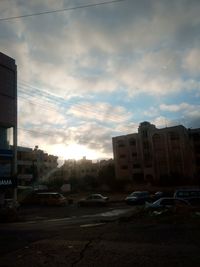 Cars on road by buildings against sky