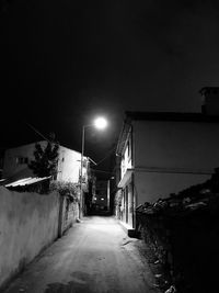 Street amidst buildings against sky at night