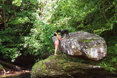 Woman standing by rock in forest