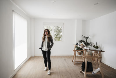 Confident businesswoman standing in modern office with hands in pockets