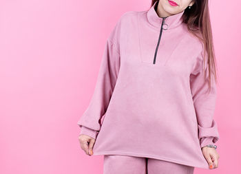 Young woman wearing soft pink pants and sweatshirt for mockup design isolated on pink background