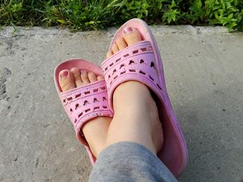 Low section of girl wearing slipper on footpath