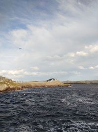 Bird flying over sea against sky