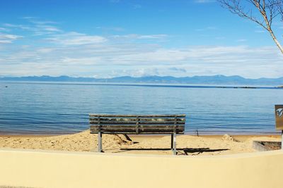 Empty bench overlooking calm blue sea