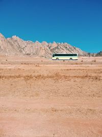 Car on desert against clear blue sky