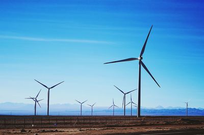 Windmills on field against sky