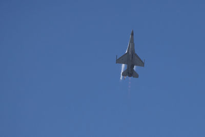 Low angle view of airplane flying against clear blue sky