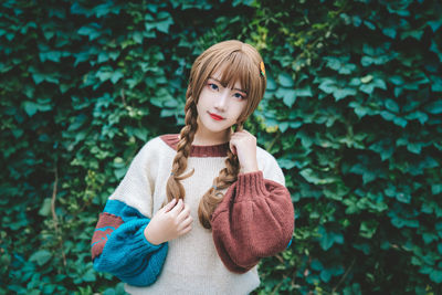 Portrait of young woman standing against plants