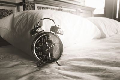 Close-up of clock on bed at home