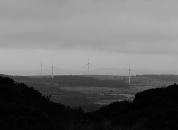 Wind turbines on field against sky