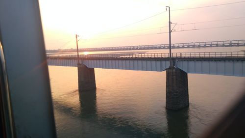 Bridge over sea against sky during sunset