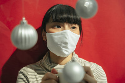 Young woman wearing mask sitting amidst hanging decoration