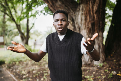 Shocked surprised young african man in park. fall or spring season