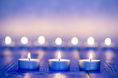 Close-up of illuminated tea light candles on table at night