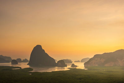 Rocks on sea against sky during sunset