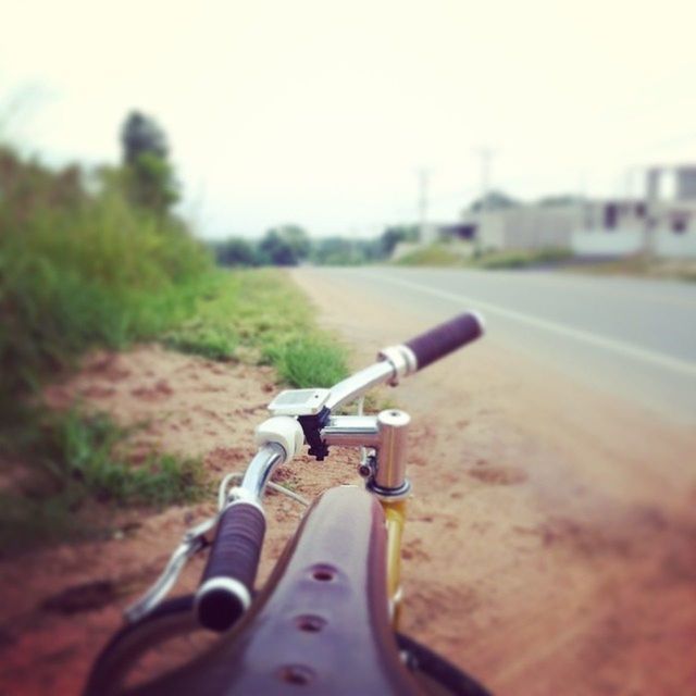 transportation, land vehicle, mode of transport, focus on foreground, selective focus, car, close-up, part of, road, cropped, bicycle, travel, day, technology, metal, field, outdoors, clear sky, on the move, landscape