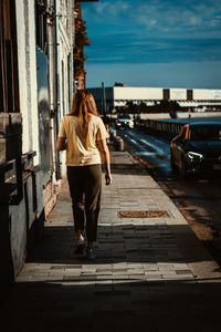 Full length rear view of woman walking on footpath