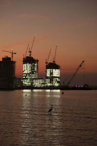 Commercial dock by sea against sky during sunset