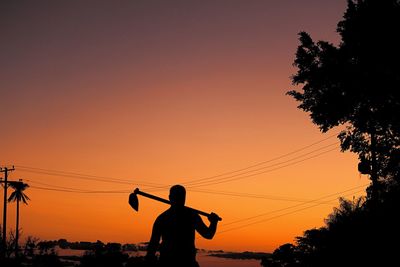 Silhouette man against orange sky during sunset