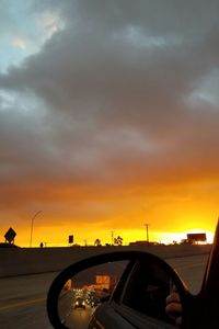 Cars on road against dramatic sky during sunset