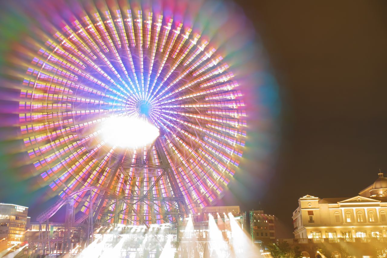 illuminated, night, building exterior, architecture, built structure, amusement park, glowing, ferris wheel, amusement park ride, arts culture and entertainment, no people, city, sky, lens flare, motion, low angle view, nature, outdoors, building, multi colored, light, fairground