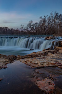 Scenic view of waterfall against sky