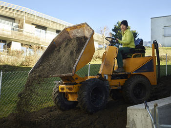 Young gardener putting soil with vehicle in garden