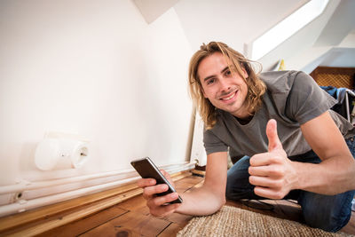 Portrait of smiling young man using mobile phone at home