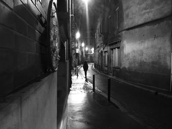 Narrow street amidst buildings in city at night