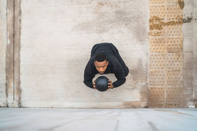 Man exercising outdoors with medicine ball against wall