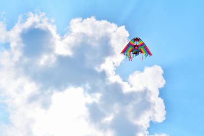 Low angle view of multi colored kite flying in cloudy sky