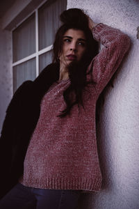 Portrait of beautiful young woman standing against wall